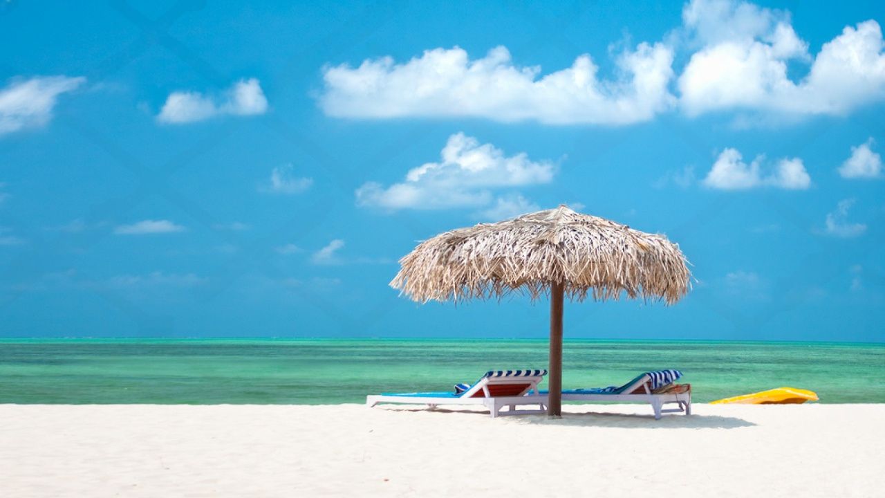 Two beach lounge chairs under a thatched umbrella on Agatti Island, offering a relaxing spot by the ocean.