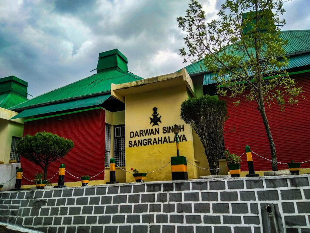 A building with a green roof and red-yellow walls, showcasing the Darwan Singh Regimental Museum in Lansdowne.