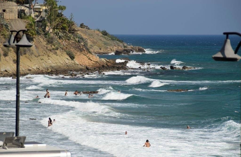 People enjoy the waves at Playa Zipolite, relaxing and playing on the sandy beach under a clear blue sky.