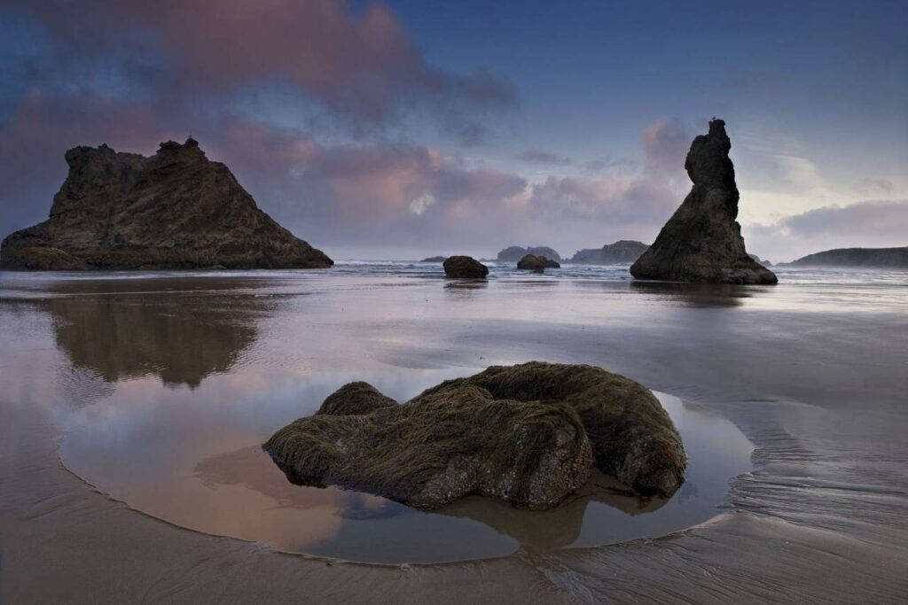 Photograph of Bandon Beach featuring rock formations reflecting in the water, captured by Jimmy Kirk.