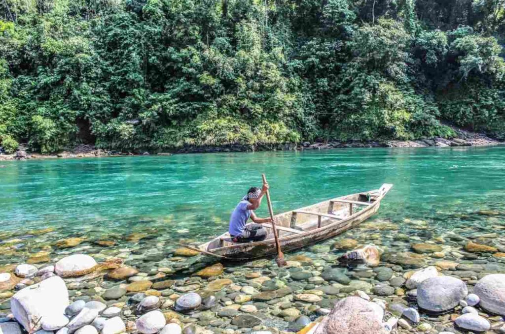 A man riding a boat in the umngot river
the cleanest river in India
