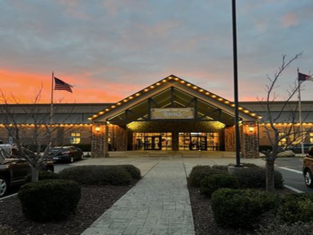 Exterior of Extreme Ice Center at sunset with glowing lights and American flags.